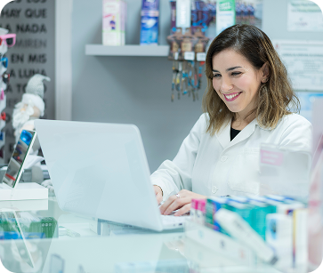 A female medical professional sitting in an eye doctors office working on her computer and smiling.