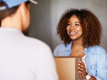 A woman accepting a package delivery from a delivery driver